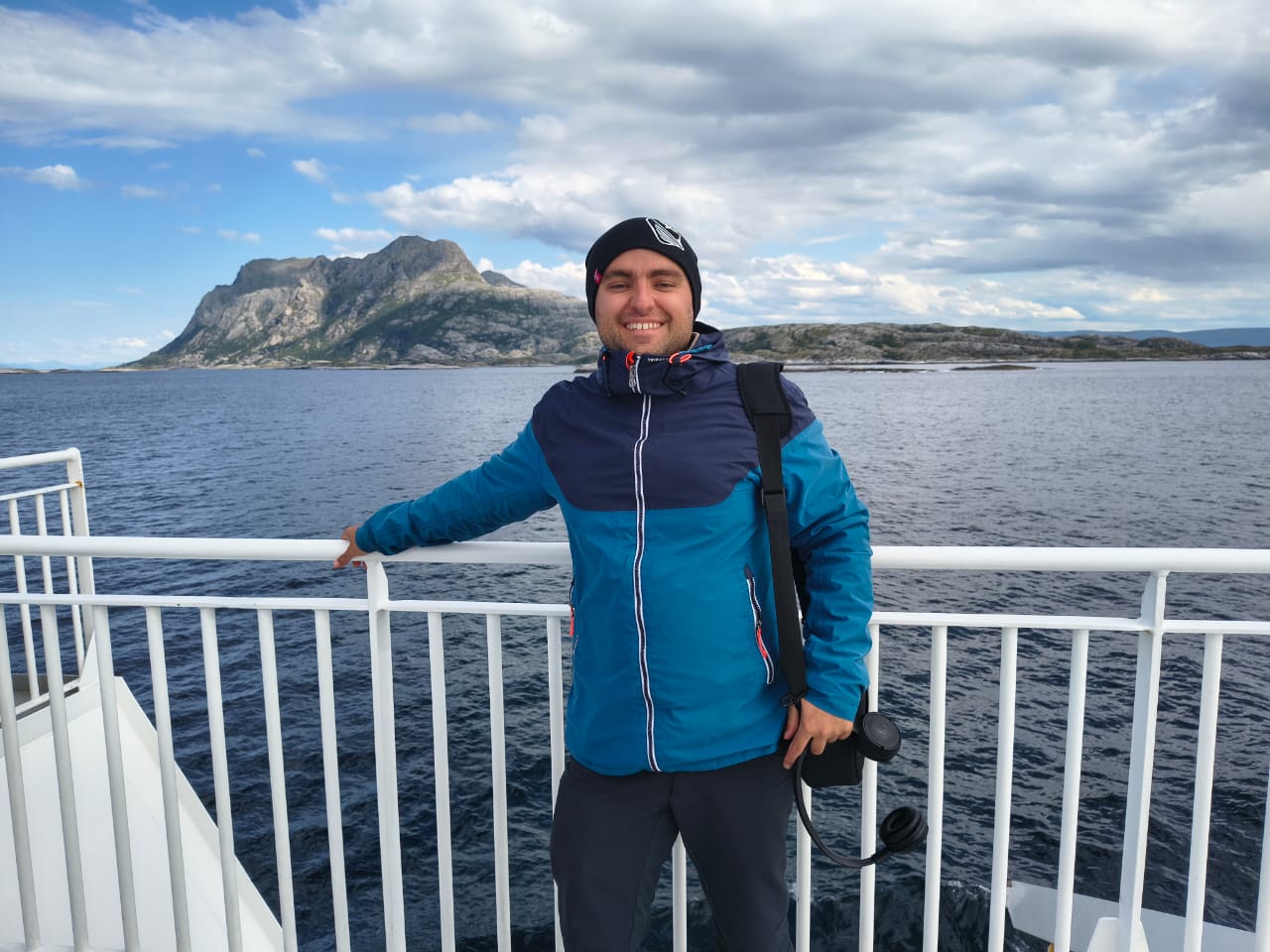 Matteo Arellano standing on a boat with mountains and sea in the background